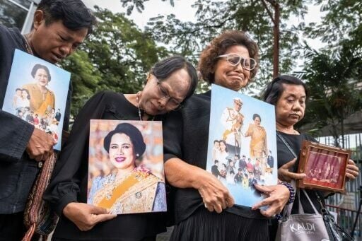 People hold portraits of Thailand's former Queen Sirikit as they gather in front of Chulalongkorn Hospital in Bangkok where she passed away late Friday